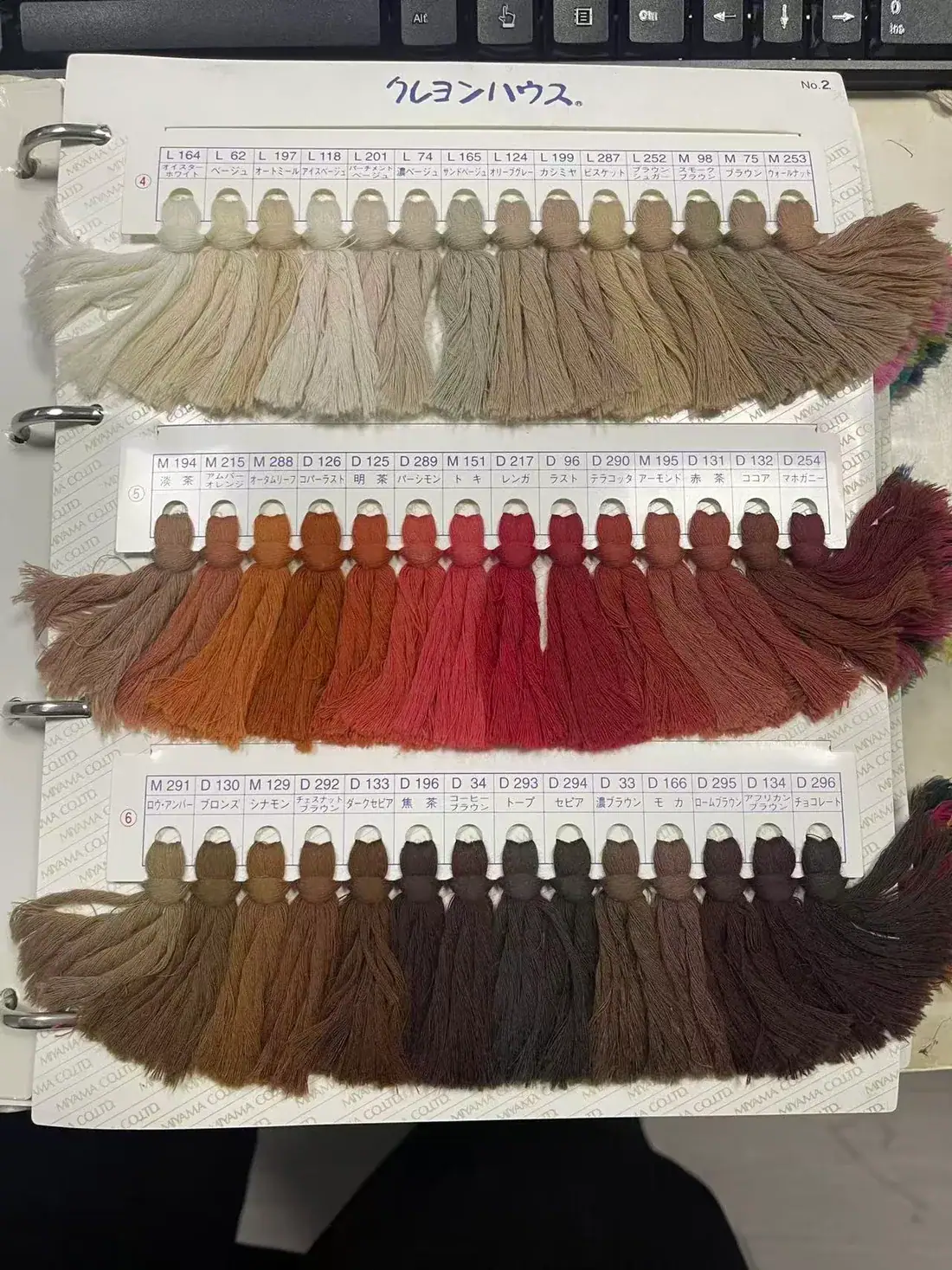 Neutral, brown and red yarn swatches in a colour book